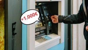 Bancomat in primo piano con mano che lo usa