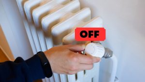 Una mano che spegne il termosifone